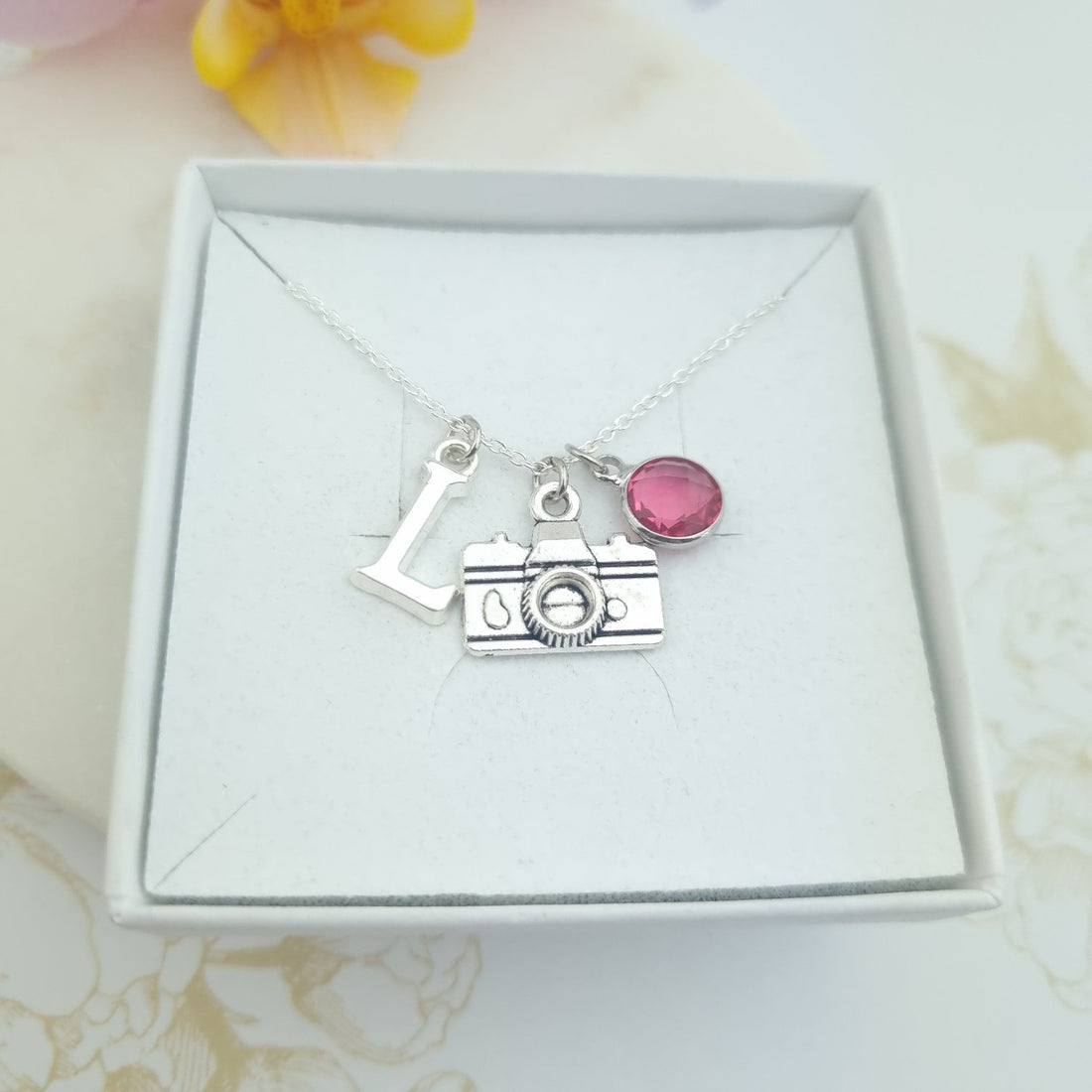 sterling silver necklace with camera charm, an initial and a birthstone in a gift box