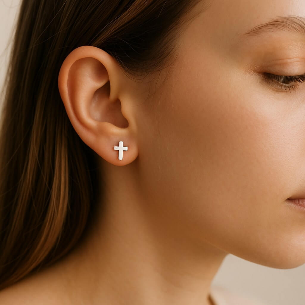 Sterling silver cross stud earrings in a minimalist 4x6mm size, shown with butterfly backs on a white background.
