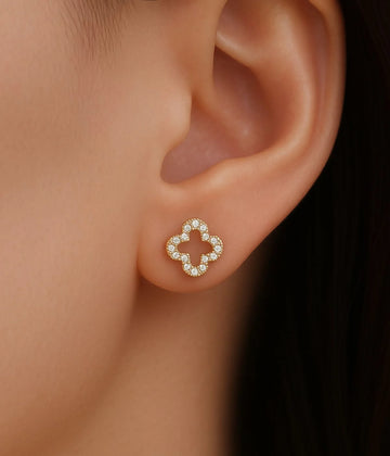 a woman wearing a shamrock gold earring