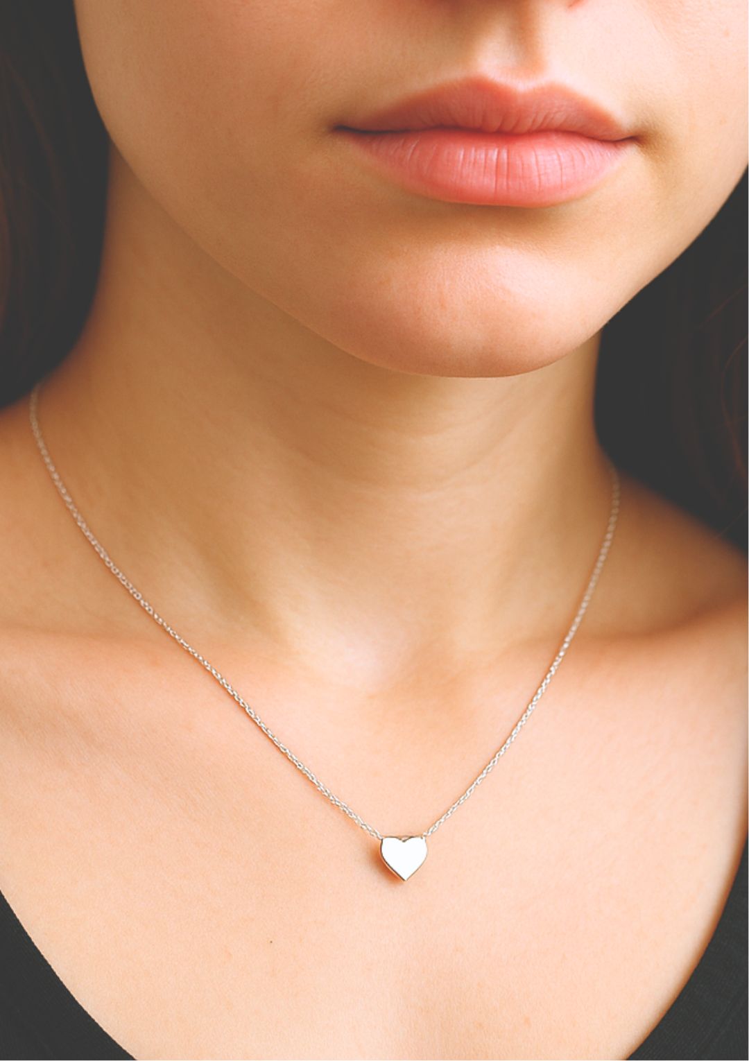 a young woman wearing a delicate heart necklace in sterling silver