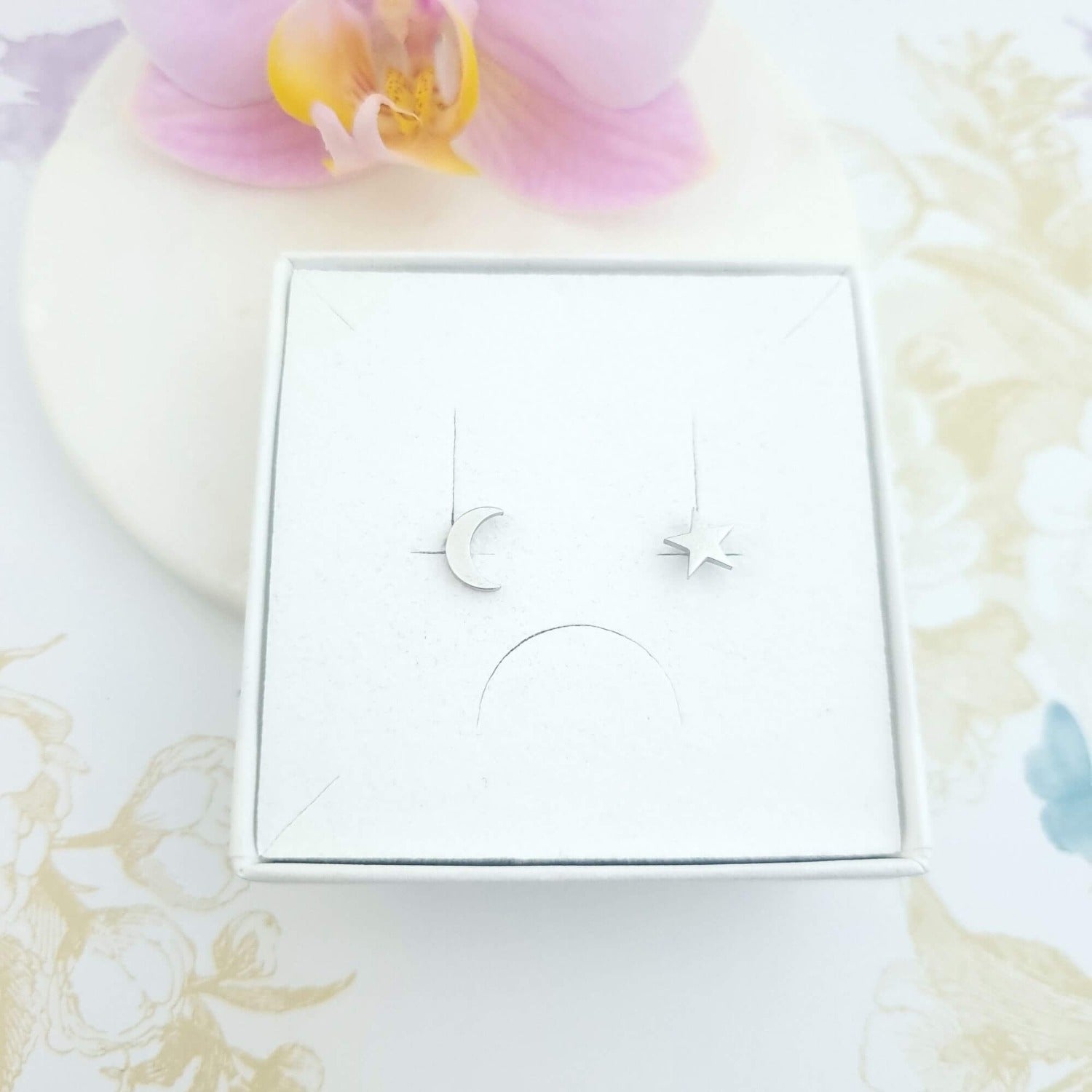 mismatched moon and star stud earrings in a gift box