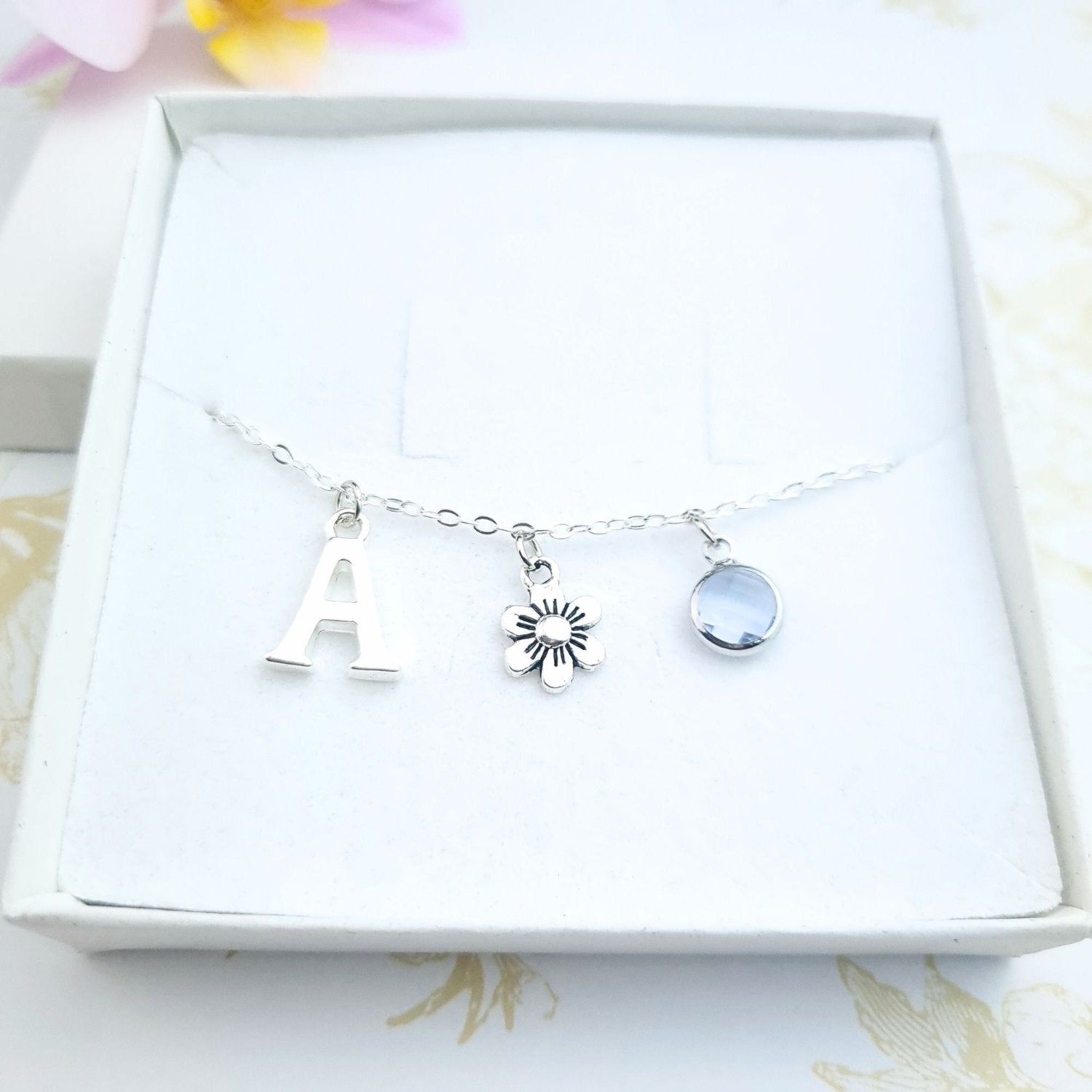 charm bracelet personalised with initial and birthstone with a daisy charm